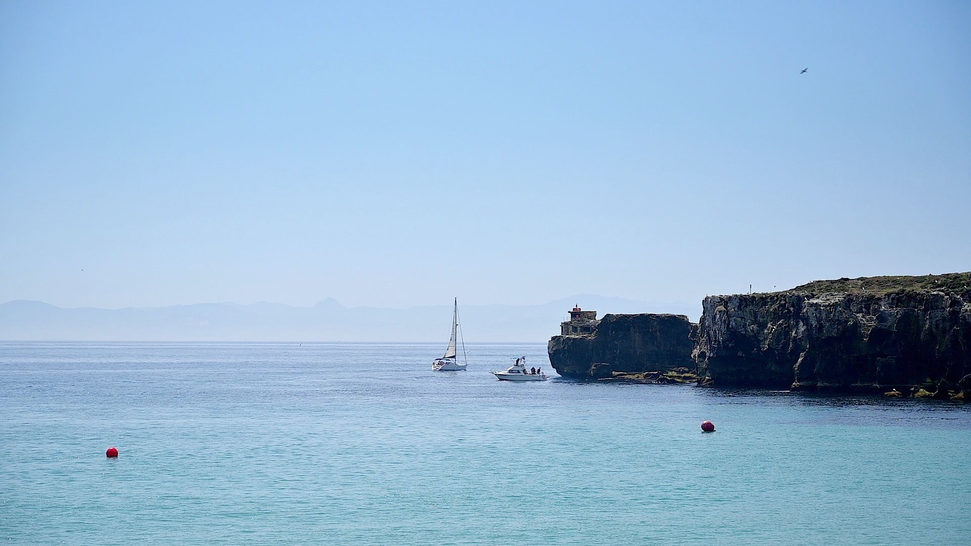 Bahía en calma junto a la Isla de las Palomas con un velero y una lancha fondeados