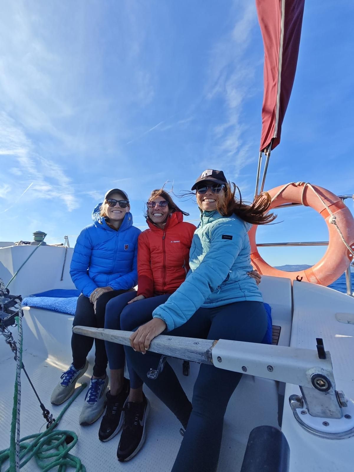 Tres amigas ríen en la cubierta del velero un día soleado navegando por el Estrecho